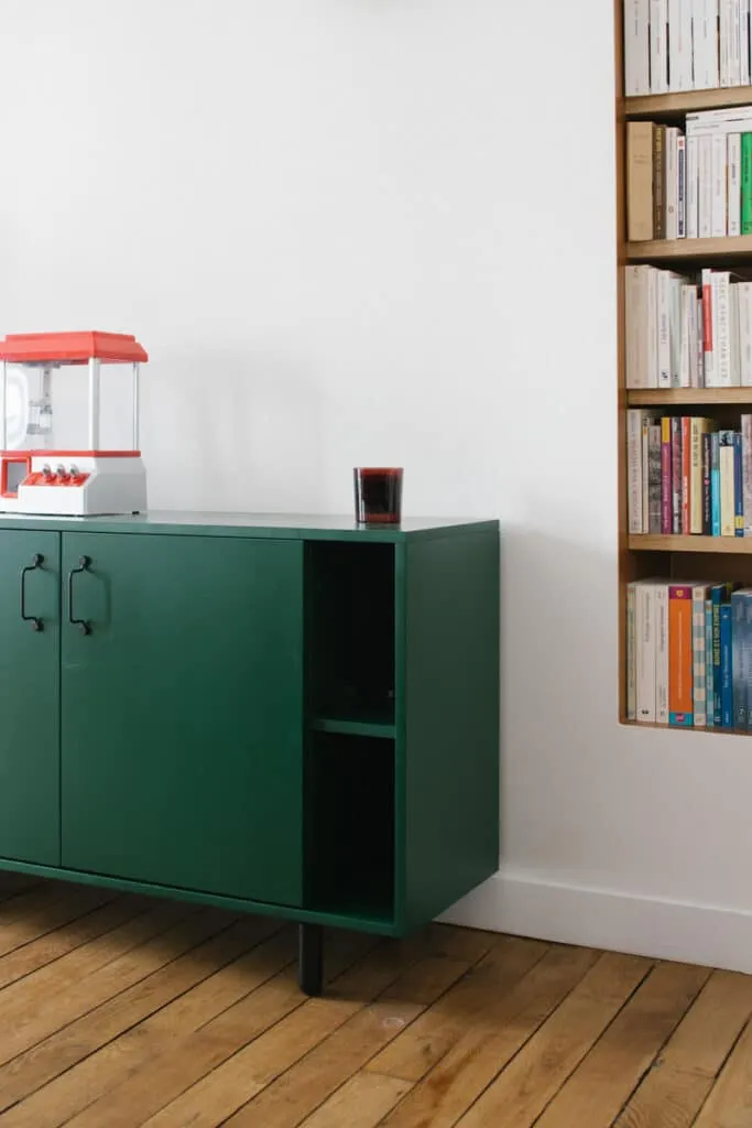 Buffet bas sur mesure laqué vert foncé à poignées noires, posé sur un parquet ancien en chêne à côté d’une bibliothèque encastrée