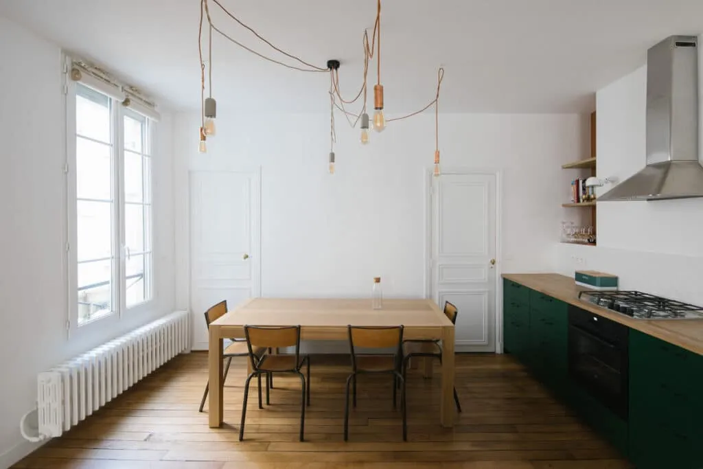 Cuisine et salle à manger rénovées avec façades vertes, table en bois et parquet ancien