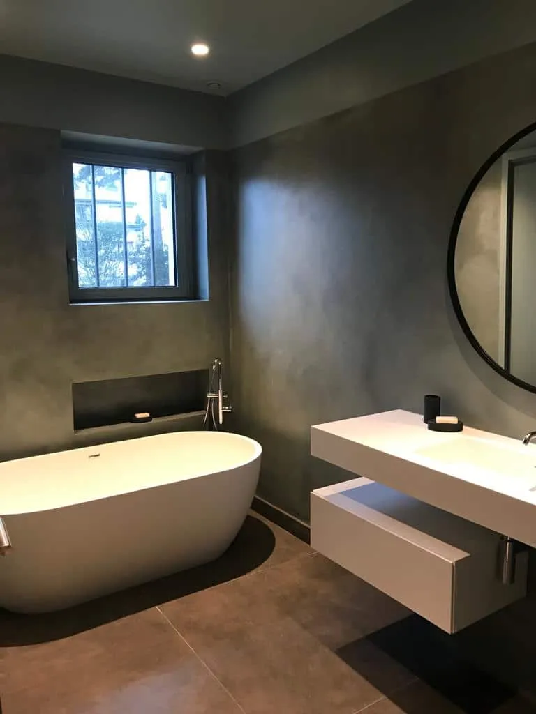 Salle de bain aux murs gris avec baignoire îlot et vasque suspendue