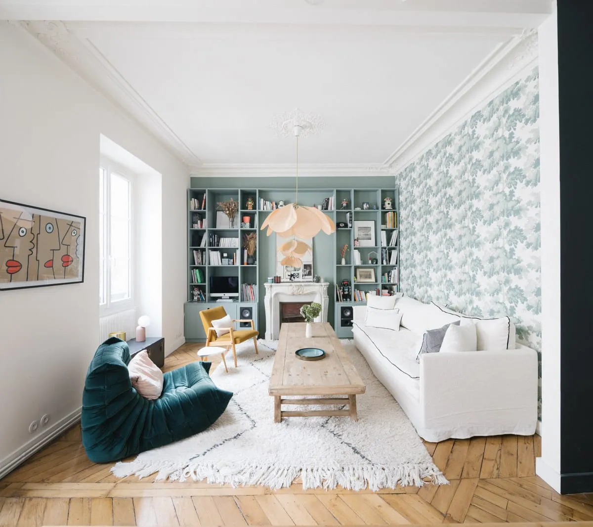 Salon parisien avec bibliothèque bleu-vert sur mesure, cheminée et parquet en point de Hongrie